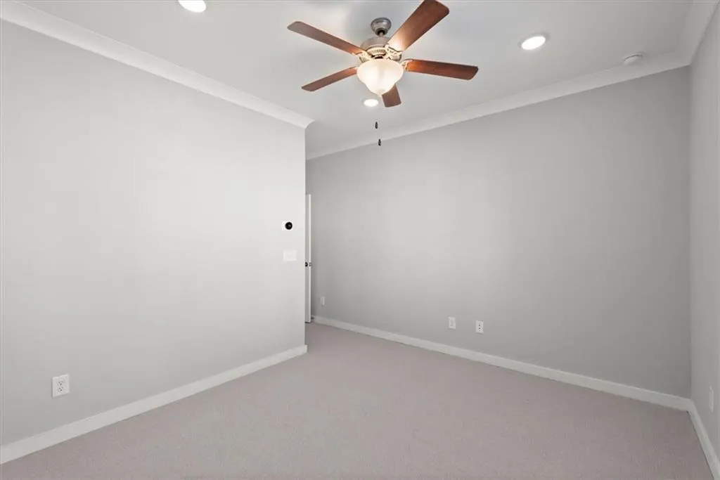 Carpeted empty room featuring crown molding, a ceiling fan, and recessed lighting