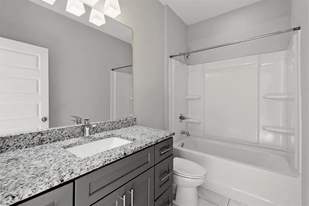 Bathroom featuring bathtub / shower combination, vanity, and light tile patterned floors