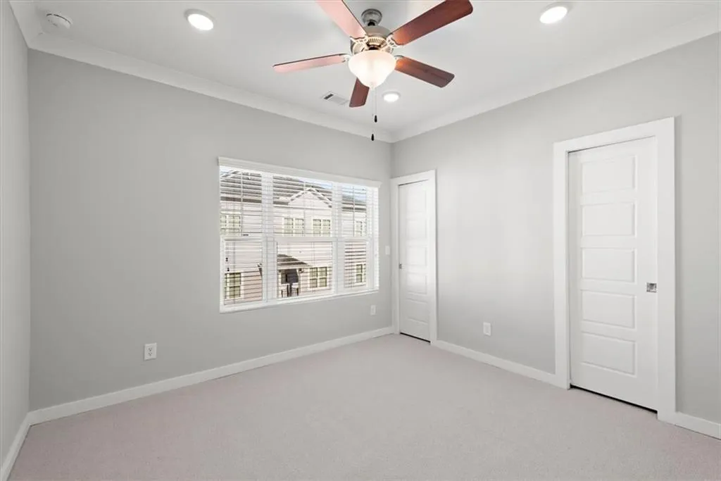 Unfurnished bedroom with light colored carpet, crown molding, recessed lighting, a ceiling fan, and two closets