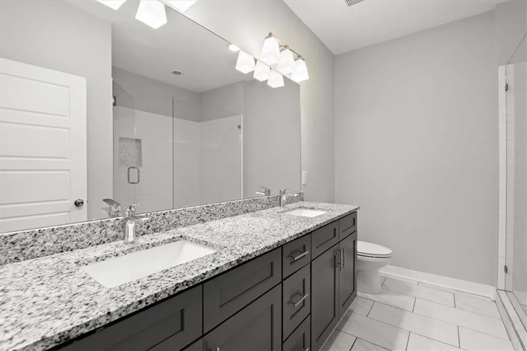 Bathroom featuring double vanity, a shower stall, and a skylight
