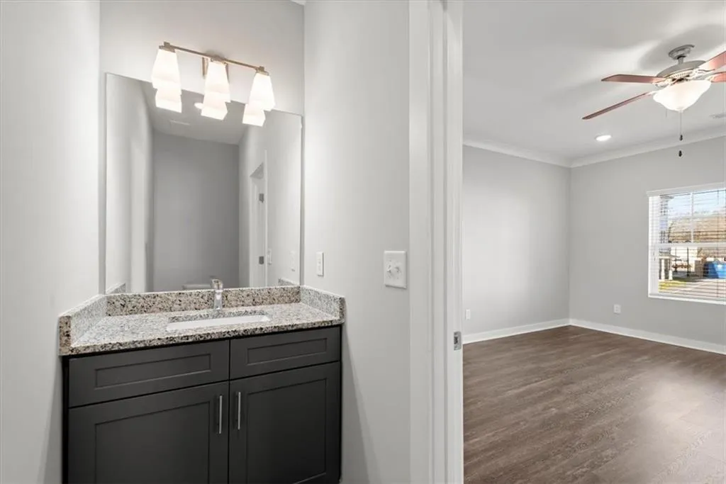 Bathroom featuring ceiling fan, vanity, dark wood finished floors, crown molding, and recessed lighting
