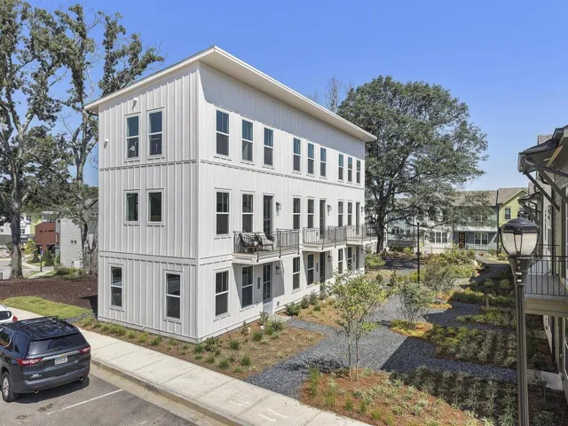 Three-story building with vertical panel siding, multiple windows, and individual balconies with metal railings