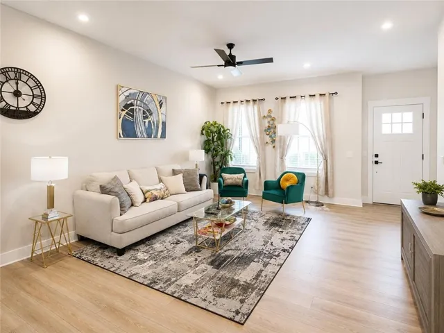 Bright and open living room featuring hardwood flooring, a cream upholstered sofa, and abundant natural light from multiple windows