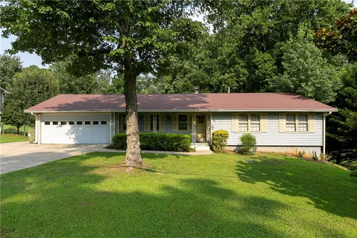 Ranch-style residence featuring light blue siding, a dark red roof, and a two-car garage with a concrete driveway