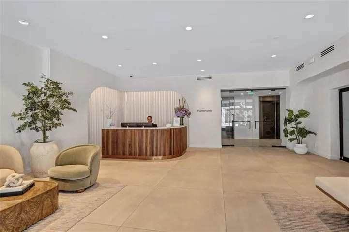 Spacious lobby with a wood-paneled reception desk, recessed lighting, and light-toned floor tiling