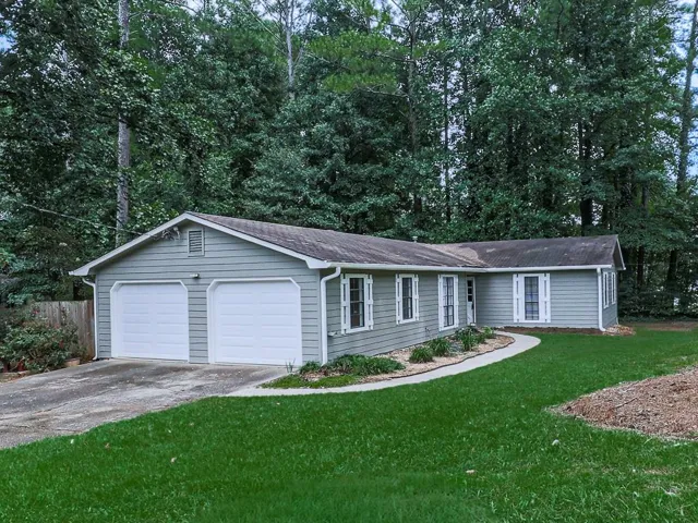 Single-story residential structure with light gray siding, white window trim, and white shutters