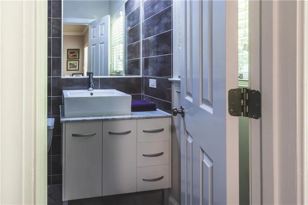 Bathroom featuring tile walls, vanity, healthy amount of natural light, and ornamental molding