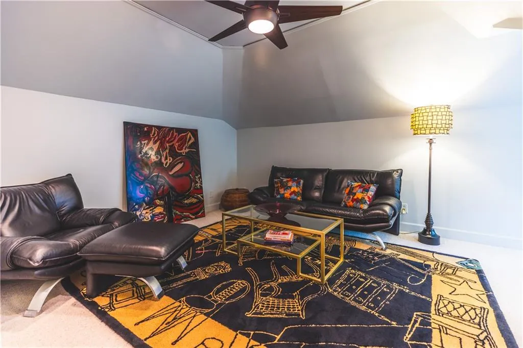 Carpeted living room with ceiling fan, lofted ceiling, and baseboards