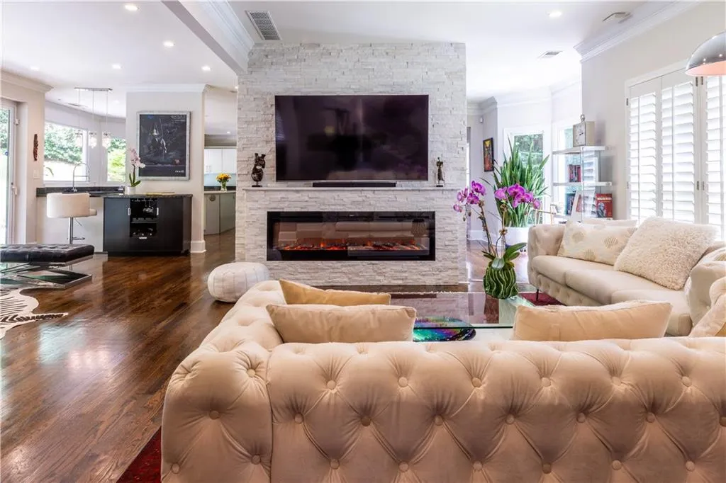 Living room featuring crown molding, wood finished floors, a stone fireplace, and recessed lighting