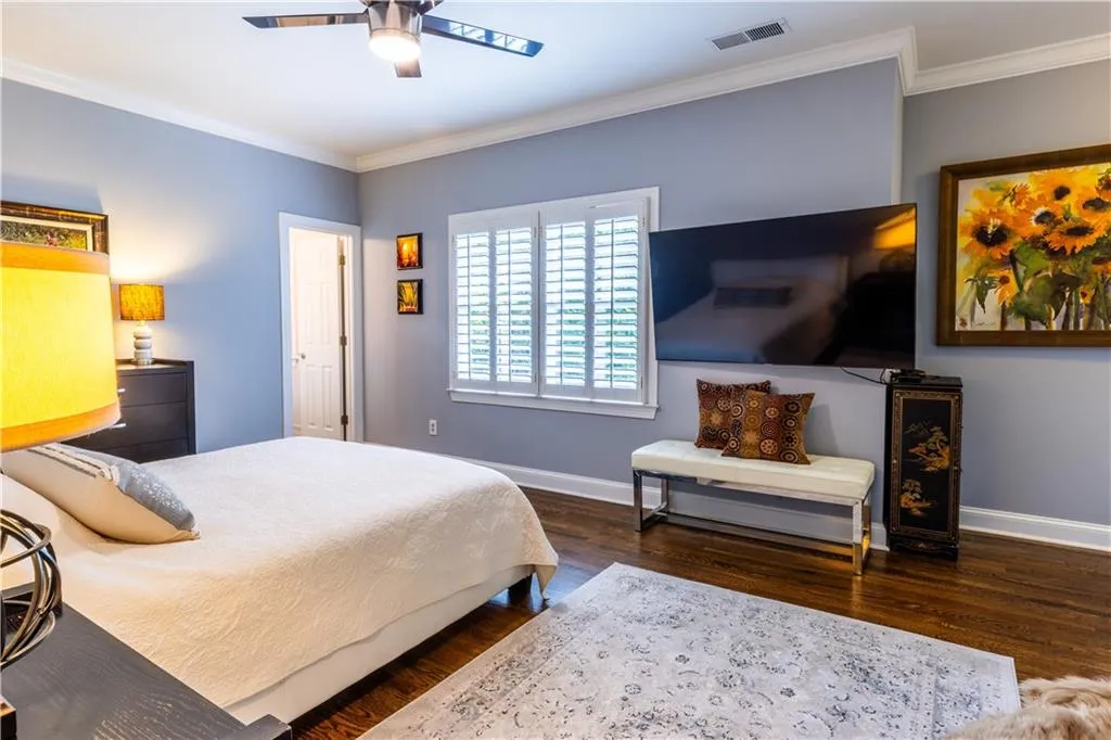Bedroom with baseboards, wood finished floors, ornamental molding, and ceiling fan