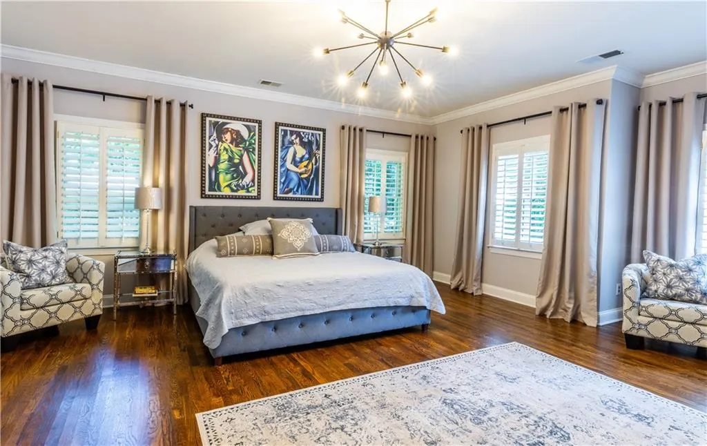 Bedroom featuring wood finished floors, a chandelier, baseboards, and crown molding