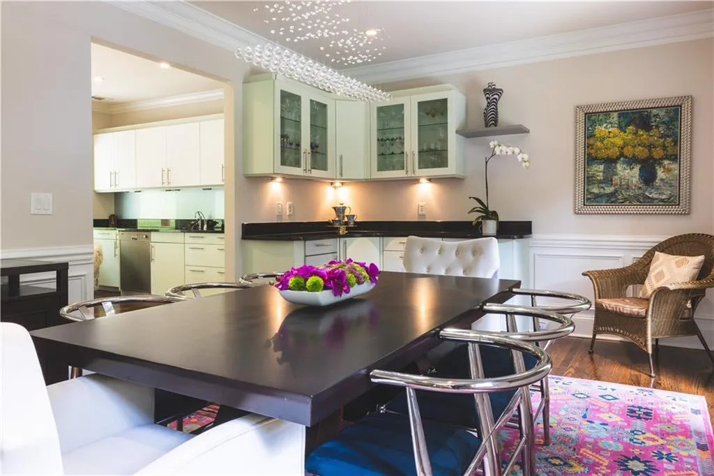 Kitchen with crown molding, wood finished floors, a sink, a wainscoted wall, and dark countertops