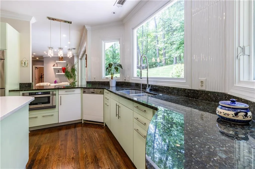 Kitchen with dishwasher, a sink, dark wood finished floors, hanging light fixtures, and ornamental molding