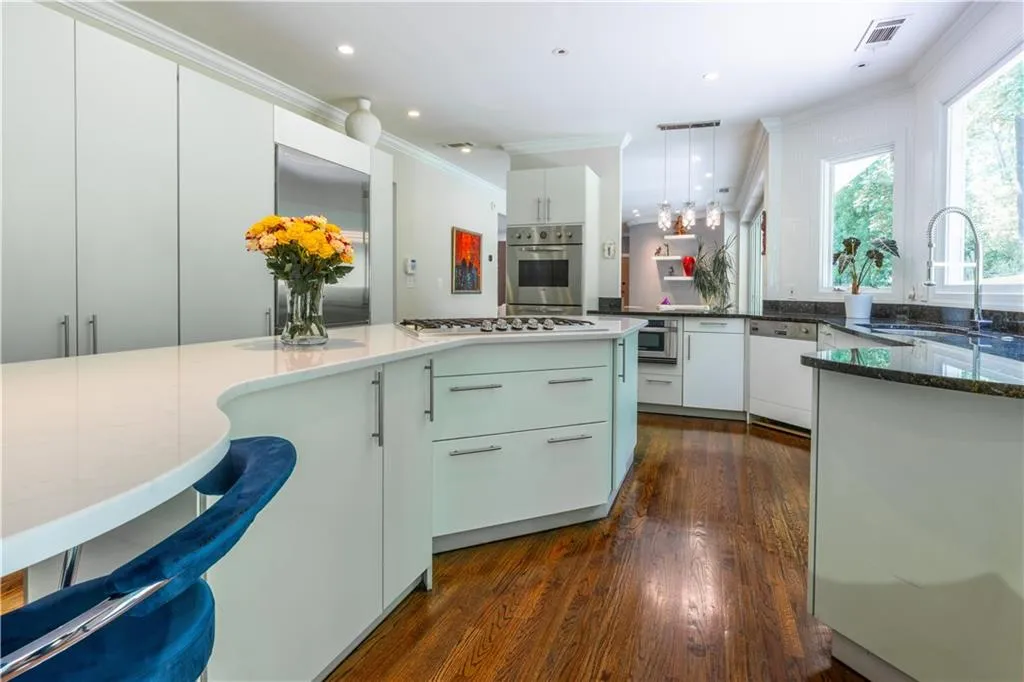 Kitchen with appliances with stainless steel finishes, a sink, ornamental molding, dark wood-type flooring, and white cabinetry