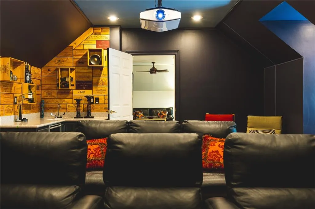 Home theater with lofted ceiling, wooden walls, a sink, and a ceiling fan