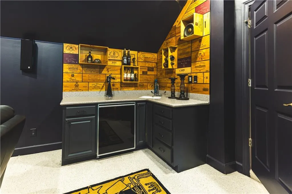 Indoor wet bar with wine cooler, lofted ceiling, and baseboards