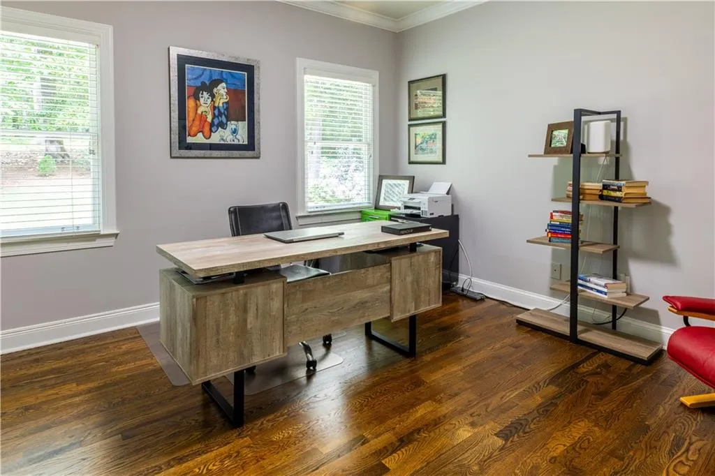 Office area with crown molding, baseboards, dark wood-style floors, and healthy amount of natural light