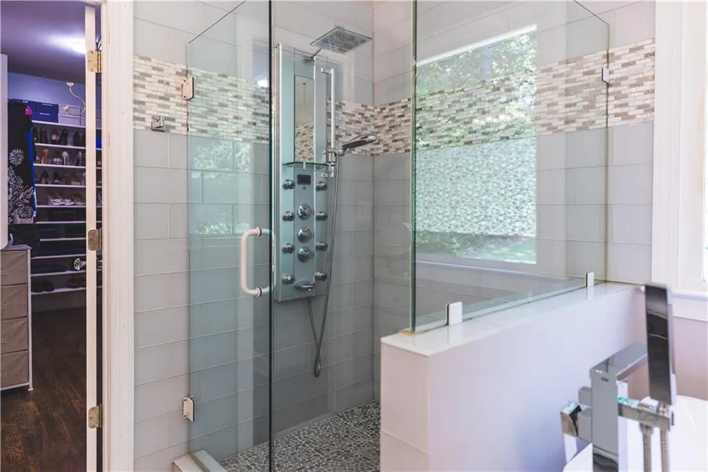 Bathroom with a shower stall and a spacious closet