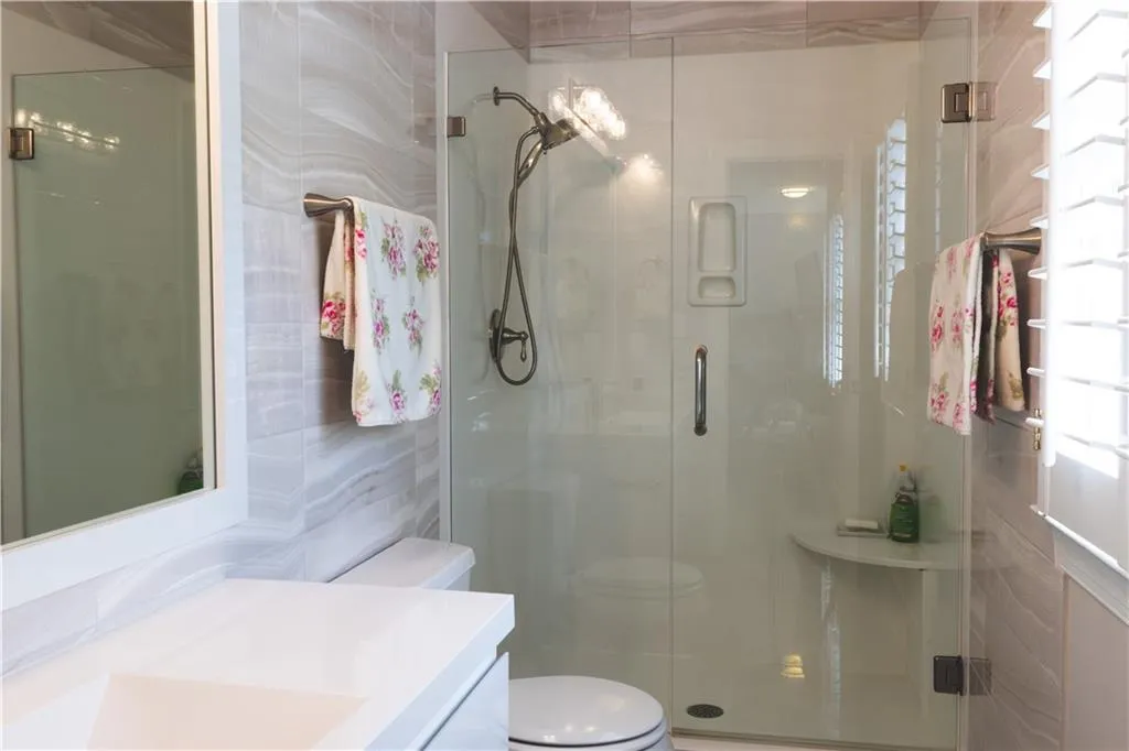 Bathroom featuring tile walls, vanity, a shower stall, and toilet