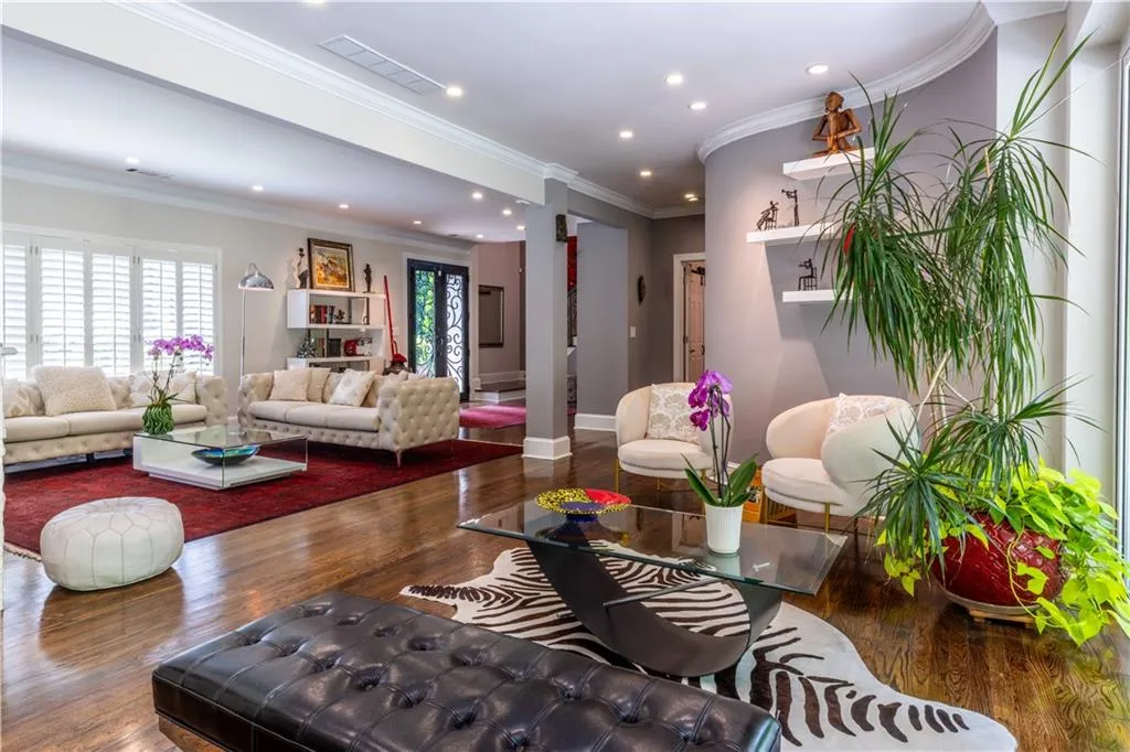 Living room featuring wood finished floors, recessed lighting, baseboards, crown molding, and ornate columns