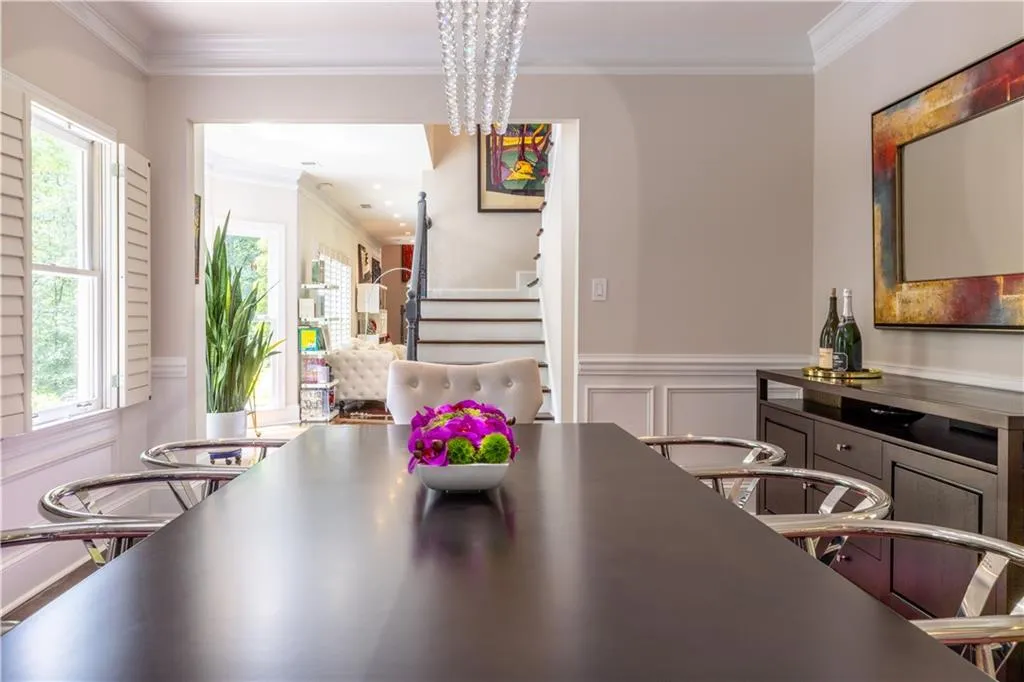 Dining area with stairway, ornamental molding, wainscoting, a chandelier, and a decorative wall