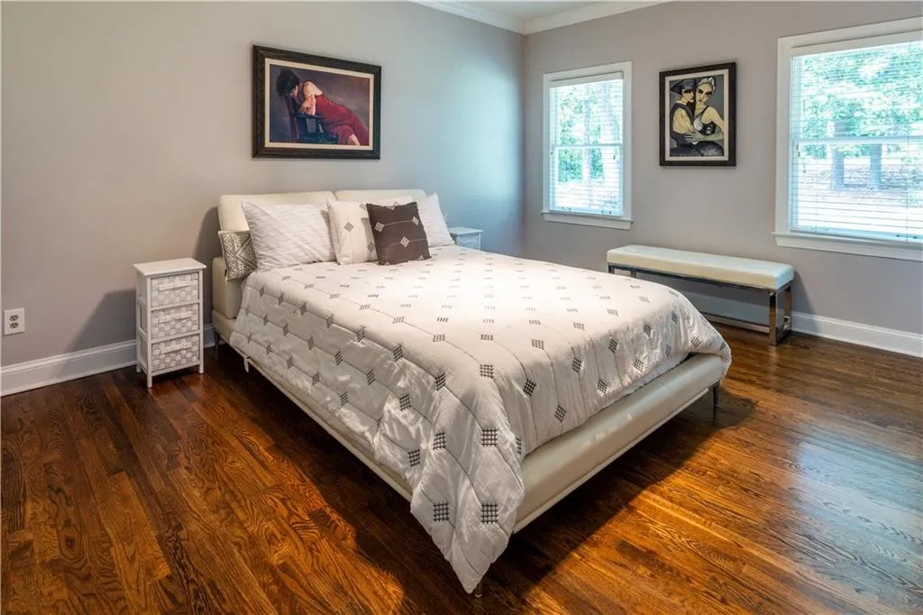 Bedroom with baseboards, ornamental molding, wood finished floors, and multiple windows