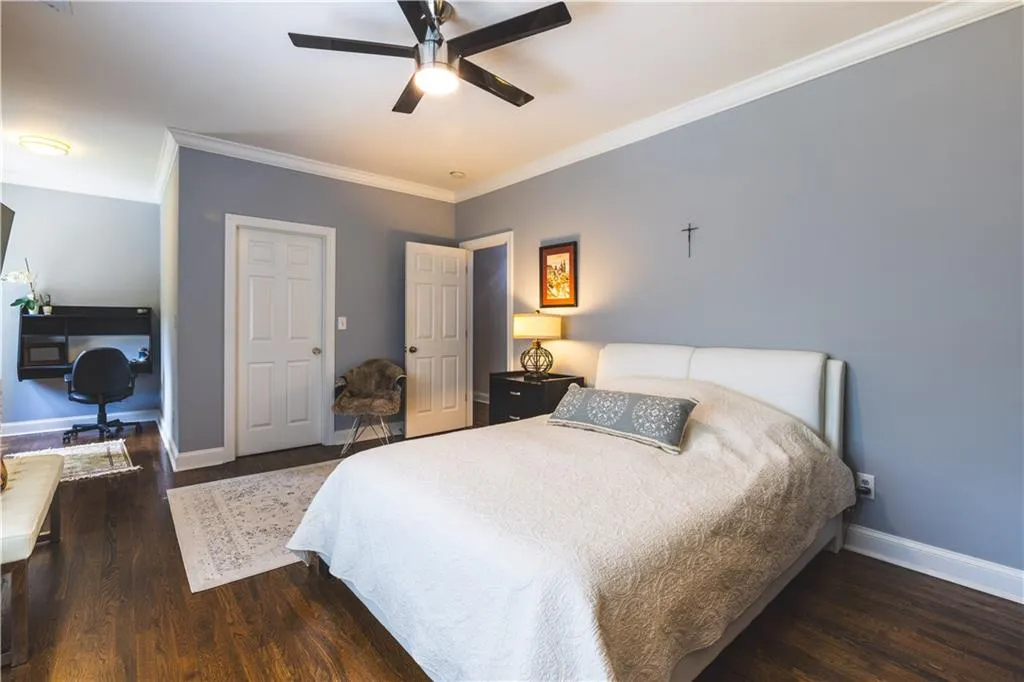 Bedroom with ornamental molding, wood finished floors, baseboards, a ceiling fan, and an office area