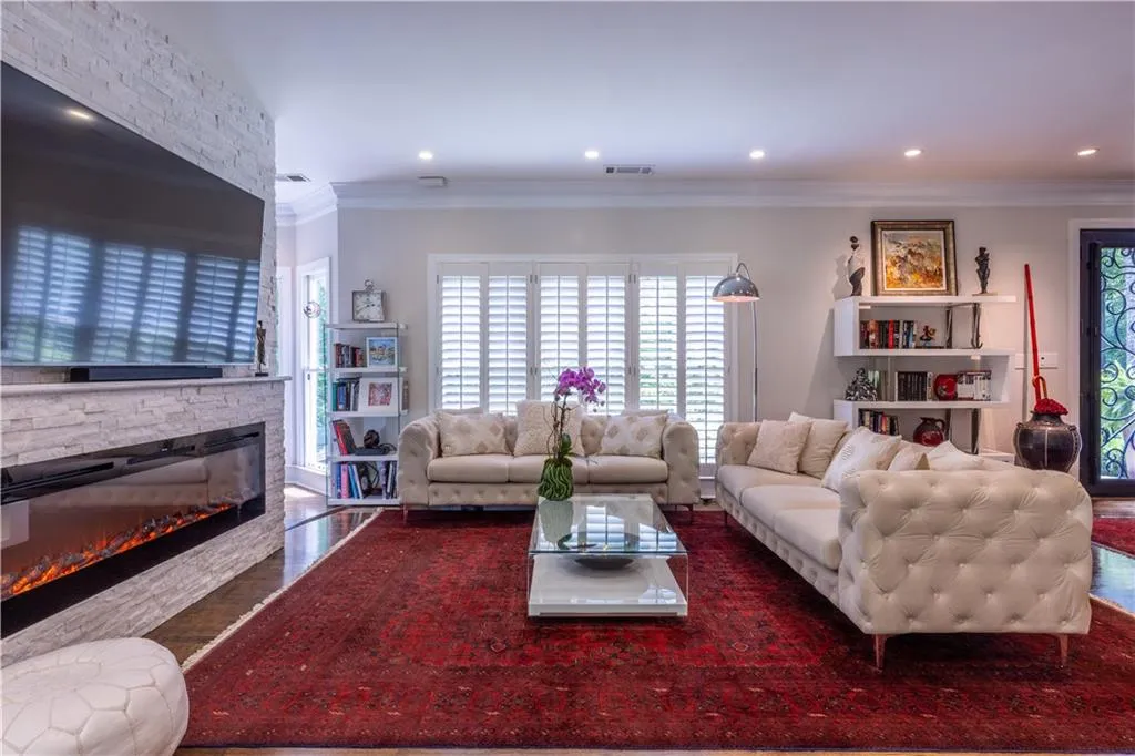 Living room featuring a fireplace, ornamental molding, wood finished floors, and recessed lighting