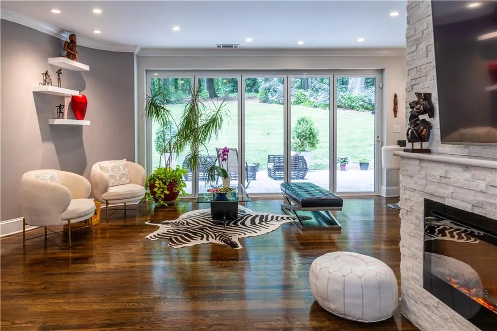 Living area featuring ornamental molding, a stone fireplace, wood finished floors, and recessed lighting