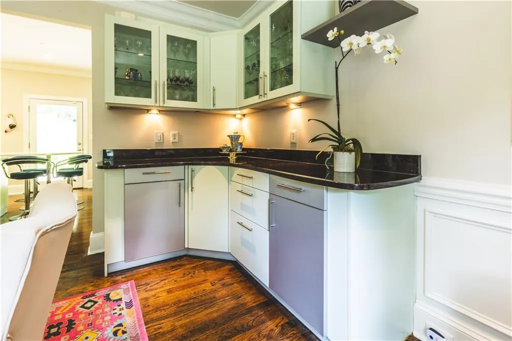 Kitchen featuring dark wood-style flooring, crown molding, and glass insert cabinets