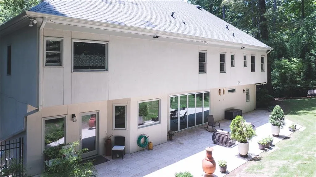 Rear view of house with a patio, stucco siding, and roof with shingles