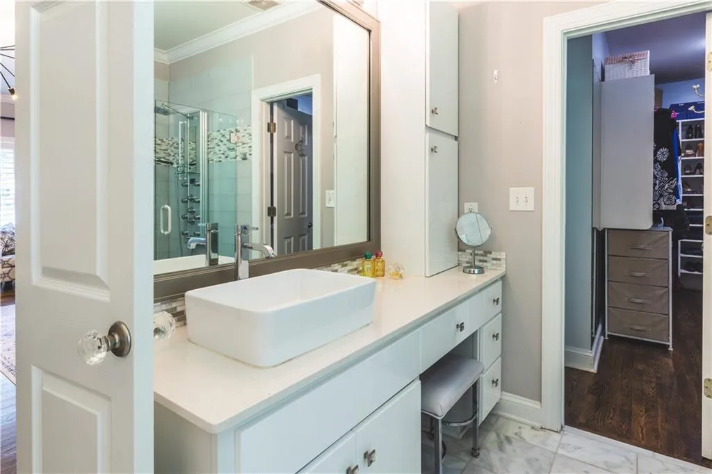 Bathroom with ornamental molding, a stall shower, vanity, a spacious closet, and marble finish flooring