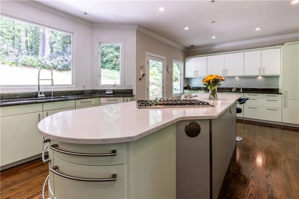 Kitchen with a sink, stainless steel gas cooktop, dark stone counters, ornamental molding, and dark wood-style flooring