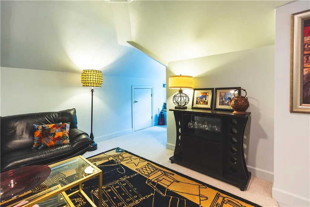 Living area featuring carpet floors, baseboards, and vaulted ceiling