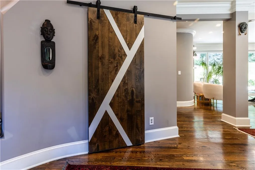 Detailed view of a barn door, wood finished floors, crown molding, and baseboards