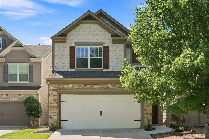 Elegant two-story residence showcasing a brick and composite exterior with a peaked gable roofline