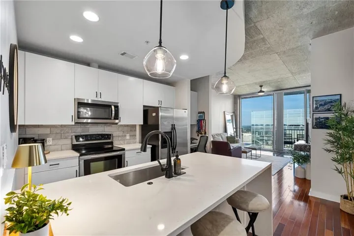 Open-concept kitchen with white cabinetry, stainless steel appliances, solid surface countertops, and a subway tile backsplash