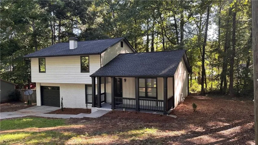 Two-story residence with white siding and dark trim, covered front porch, attached garage with dark door, and a shingled roof