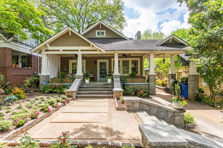 Craftsman-style facade with a covered porch, stone column bases, a portico, a multi-tier walkway, and extensive landscaping