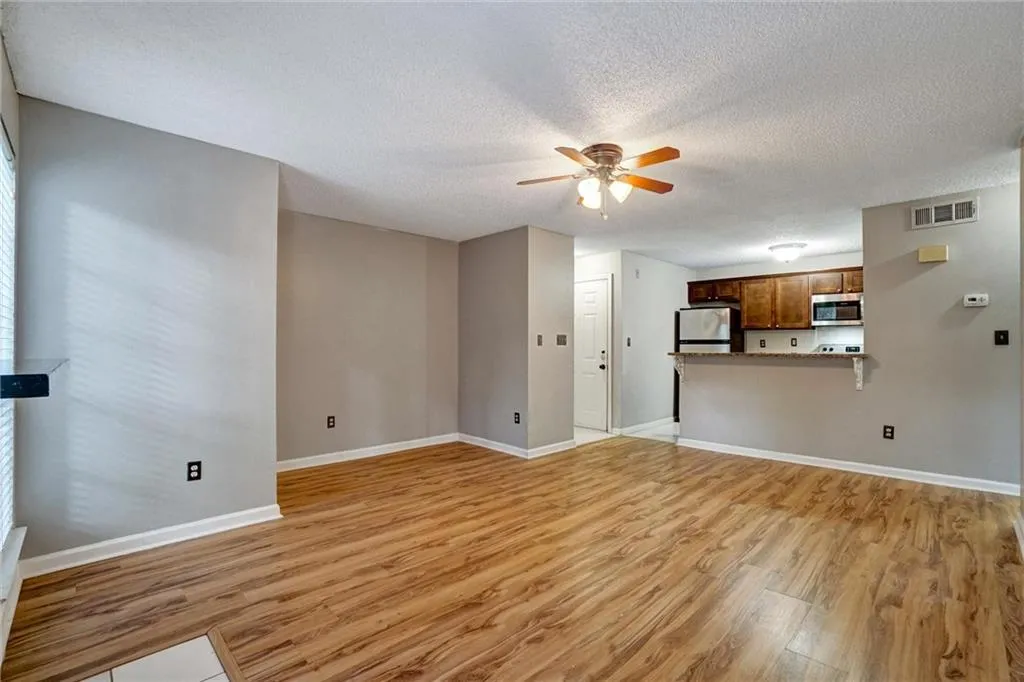Unfurnished living room with light wood-style floors, a textured ceiling, and ceiling fan