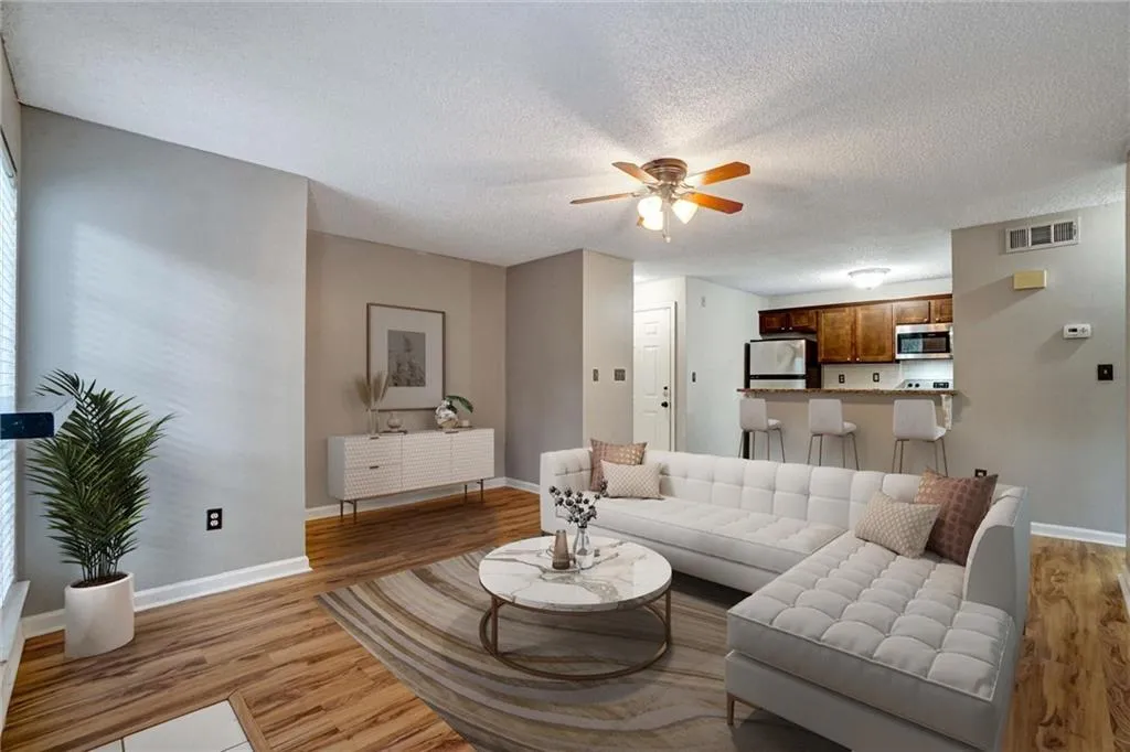 Living area with light wood finished floors, a textured ceiling, and ceiling fan