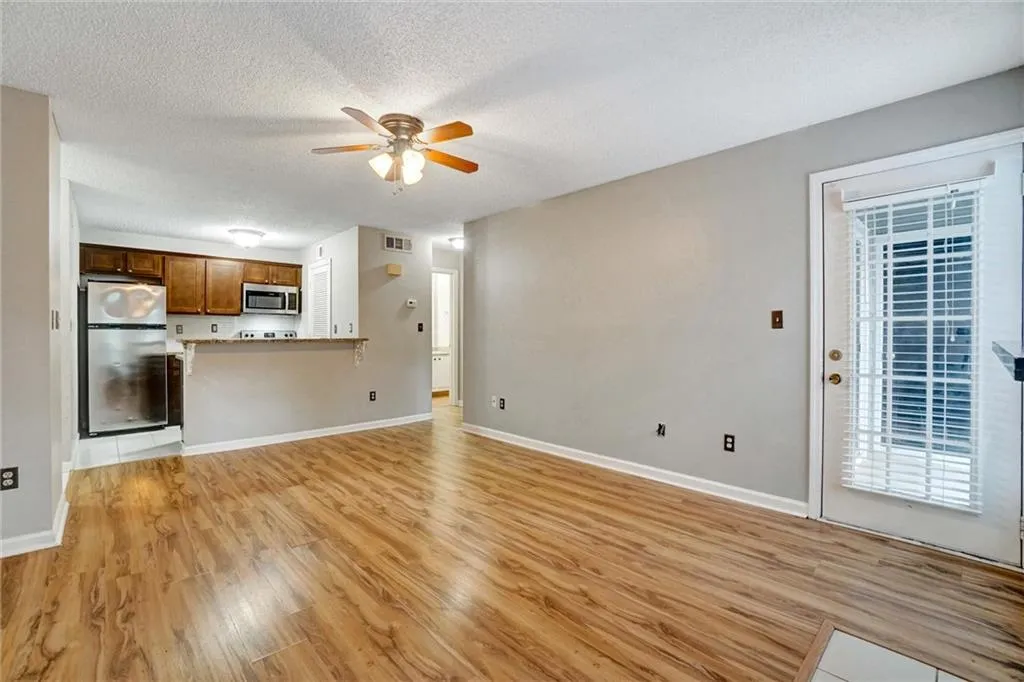 Unfurnished living room with a textured ceiling, light wood-style floors, and a ceiling fan