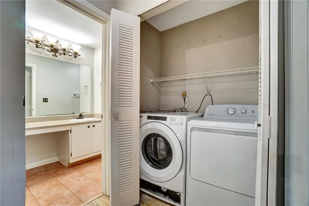 Washroom featuring light tile patterned flooring and washer and clothes dryer