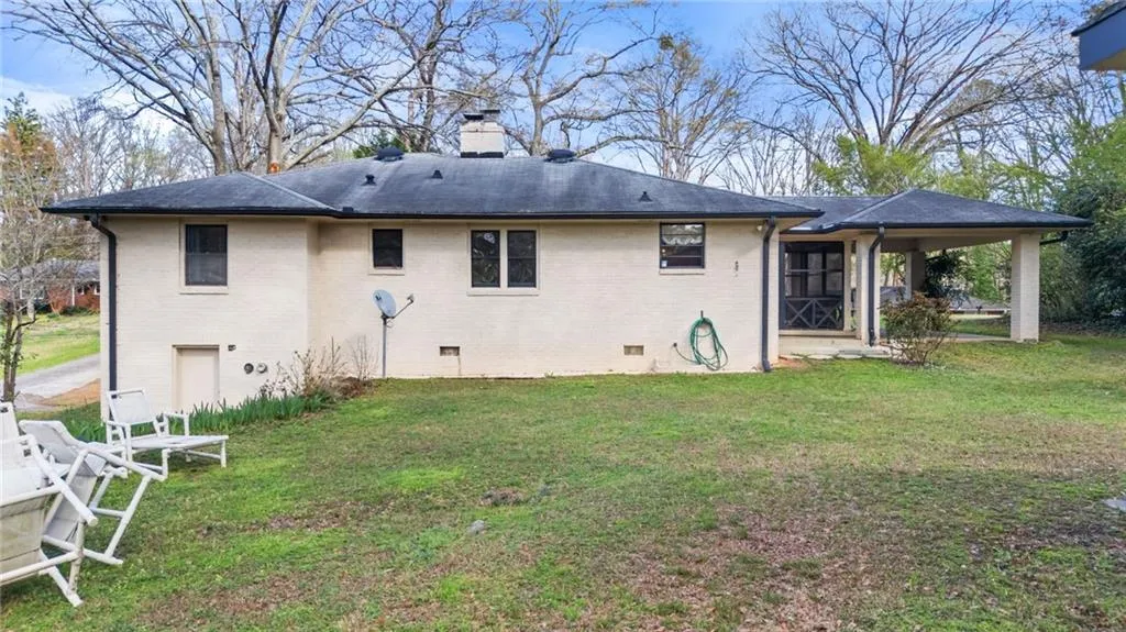 Back of property featuring crawl space, a yard, a chimney, and brick siding