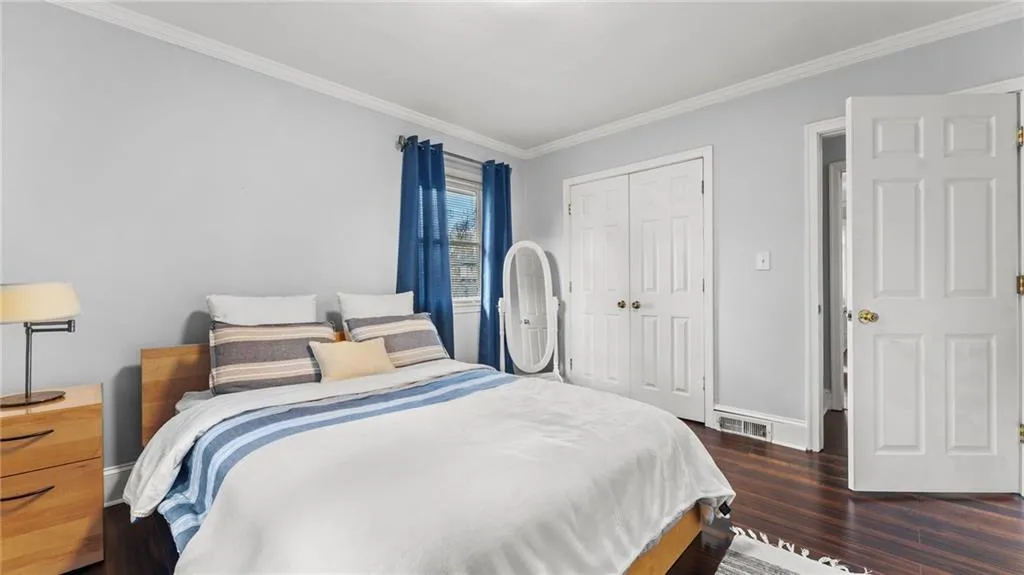 Bedroom featuring ornamental molding, a closet, and dark wood-style floors