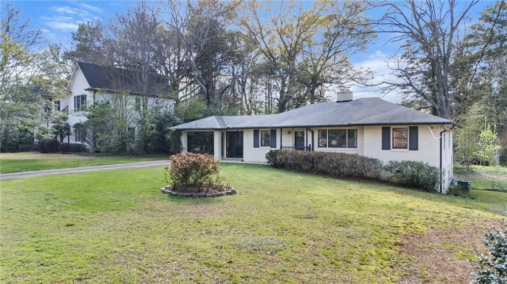 View of front of home with a chimney, a front yard, driveway, and brick siding