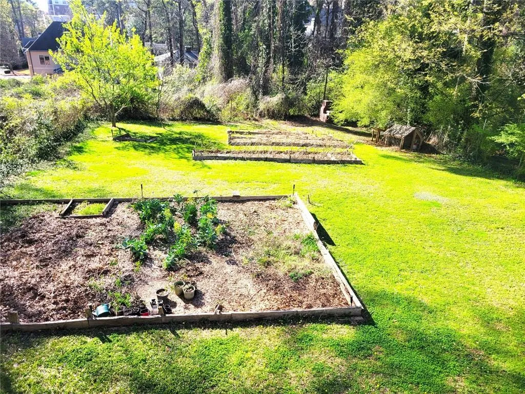 View of green lawn with a vegetable garden and view of scattered trees