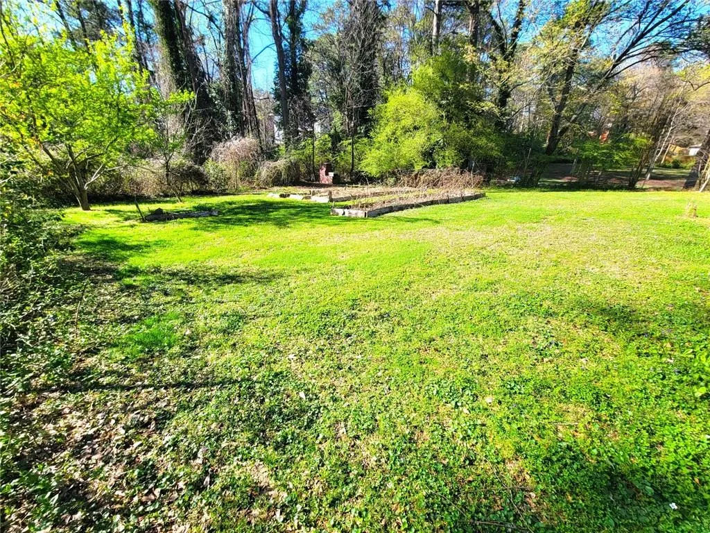 View of green lawn featuring a garden and view of wooded area
