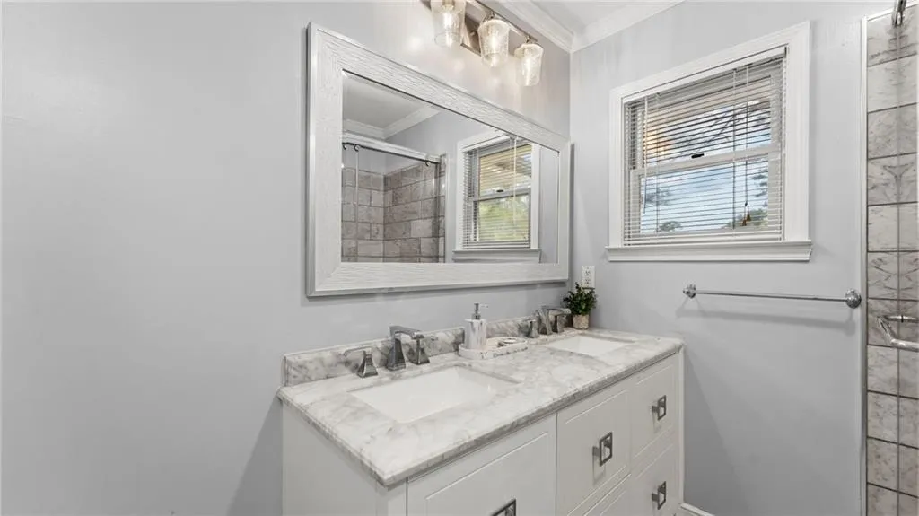 Bathroom with ornamental molding, double vanity, and a stall shower