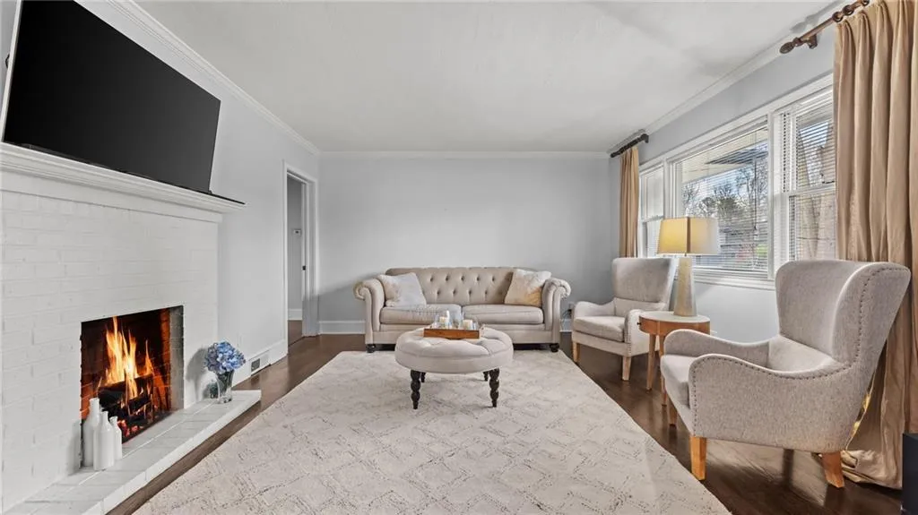 Living room with ornamental molding, a brick fireplace, and dark wood finished floors